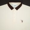 Beige polo shirt with brown collar and fils logo on a black background