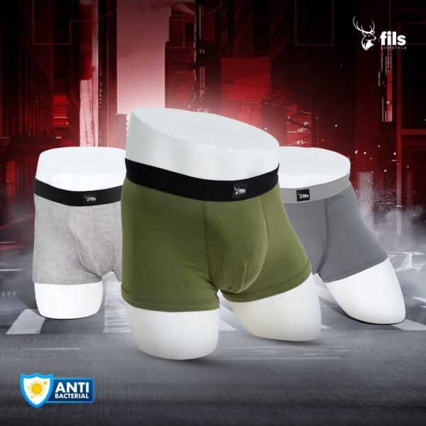 Three pairs of men's underwear in green, gray, and white on a dark background with 'fils' branding.